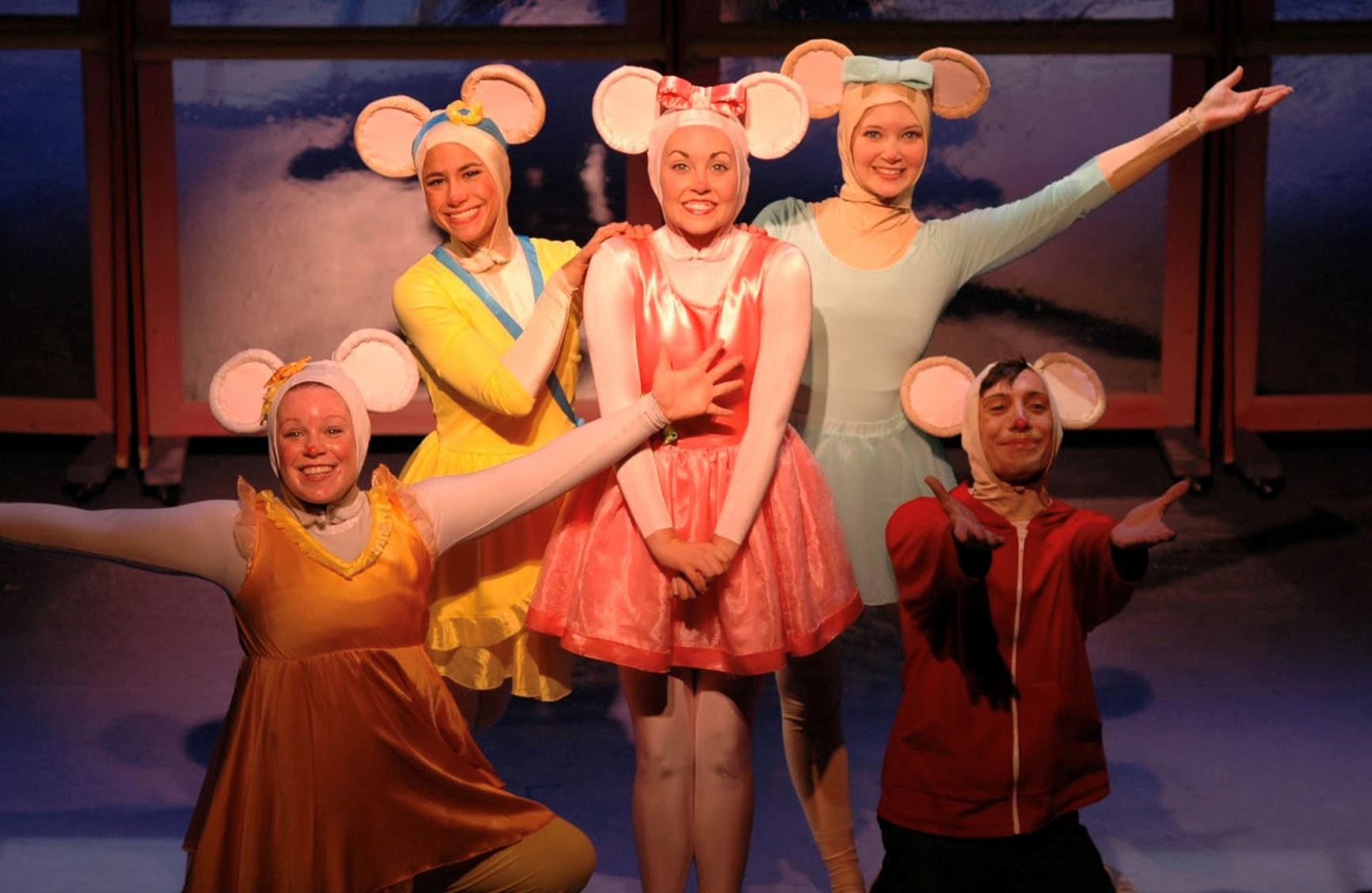 a group of 5 people on stage wearing mice costumes performing