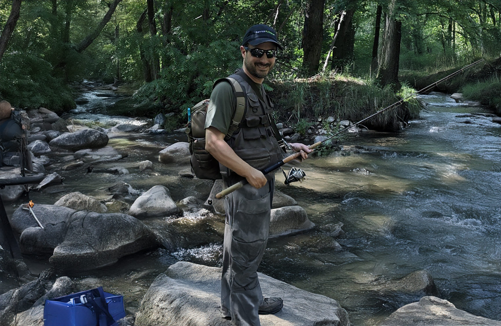 a middle aged man standing by a river prepared to start fishing
