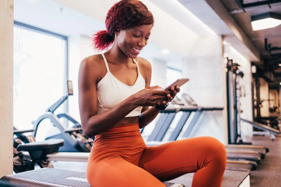 A lady using her phone in the gym.