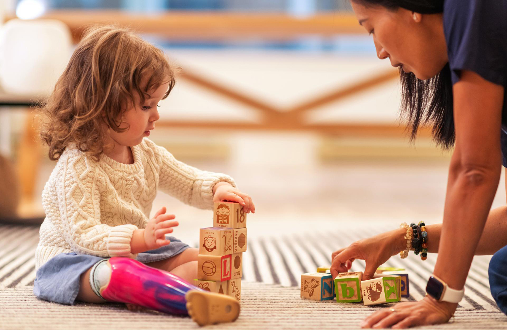 a young girl and a older woman playing with blocks on the floor