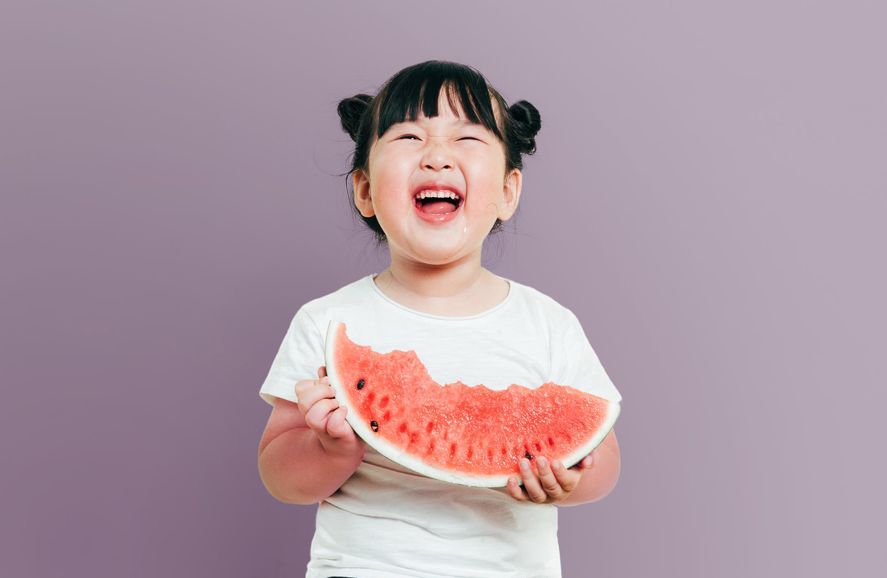 young asian girl smiling and eating watermelon