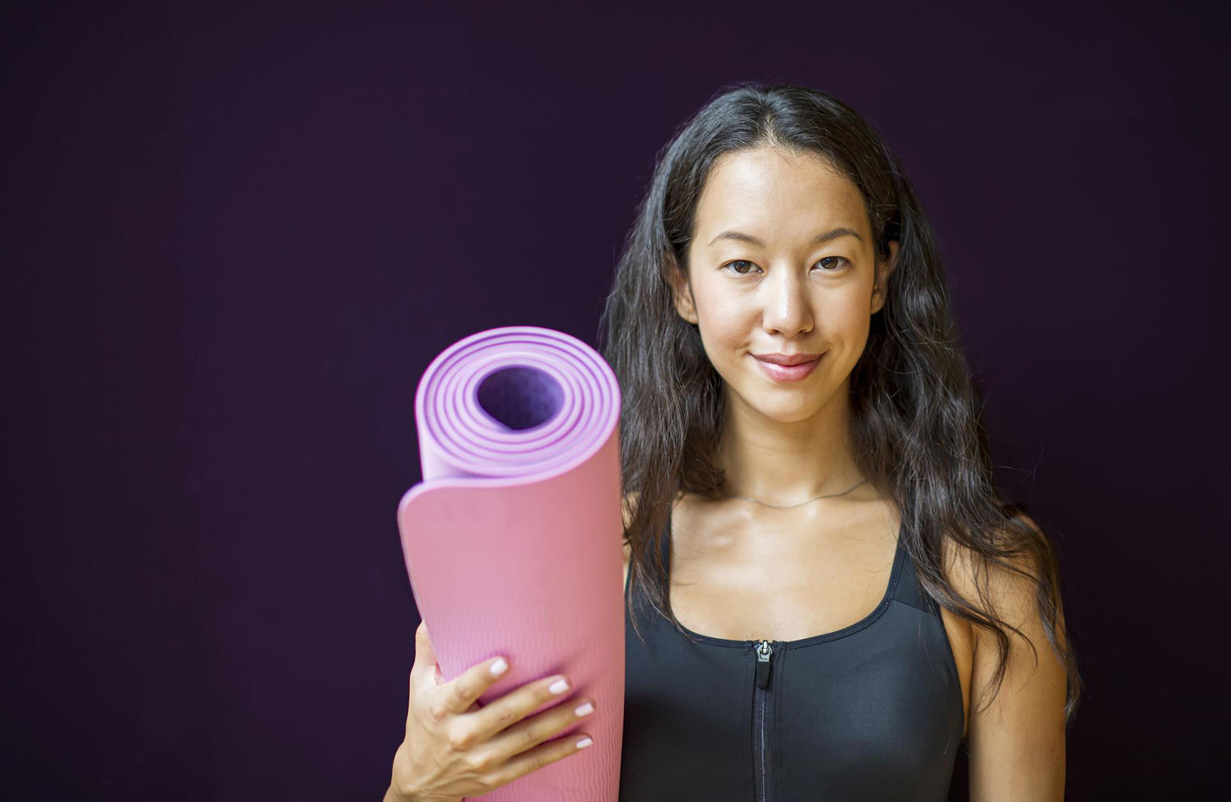 young athletic woman holding a yogo mat