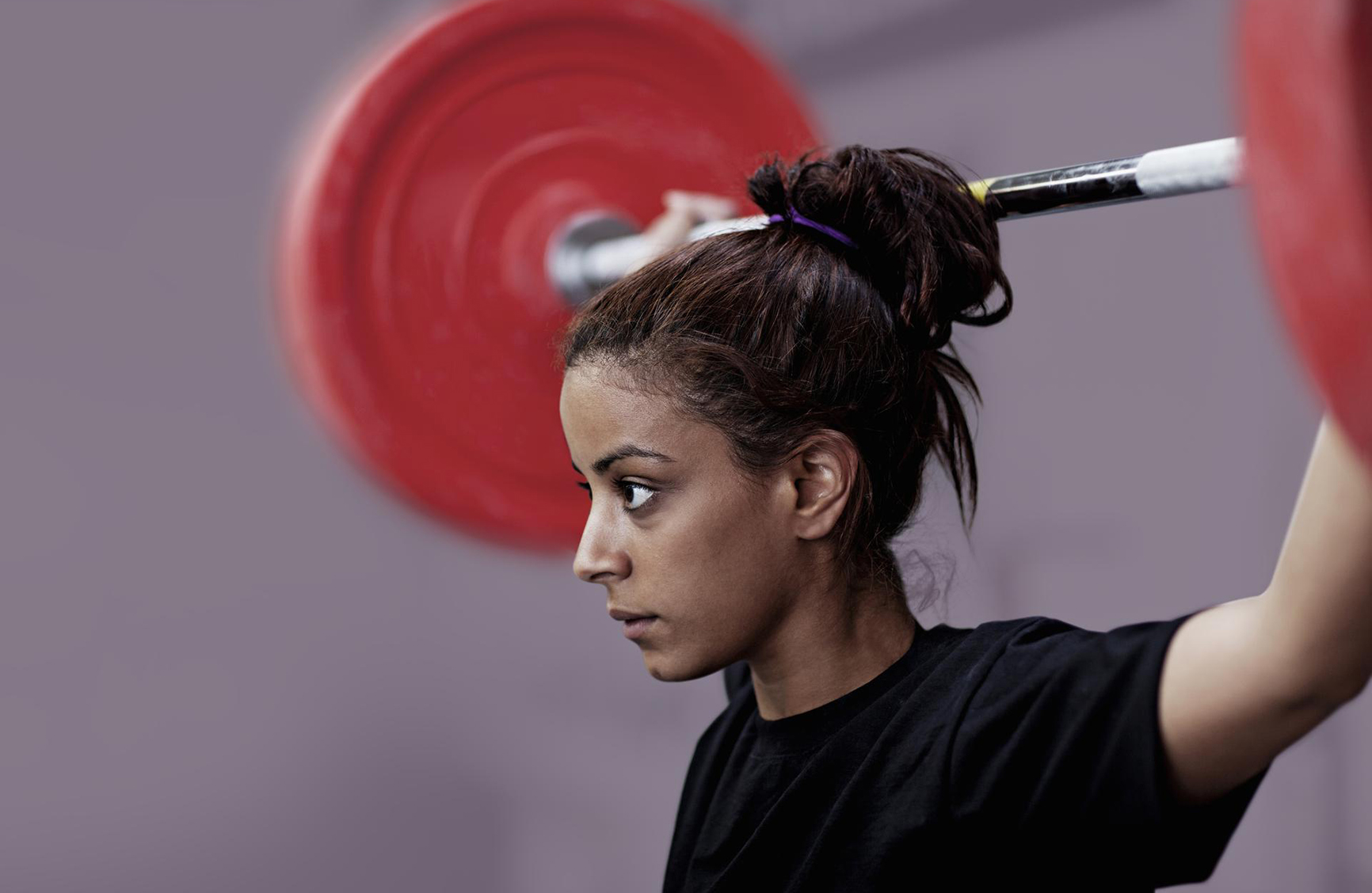 an athletic woman holding a weighted bar above her head