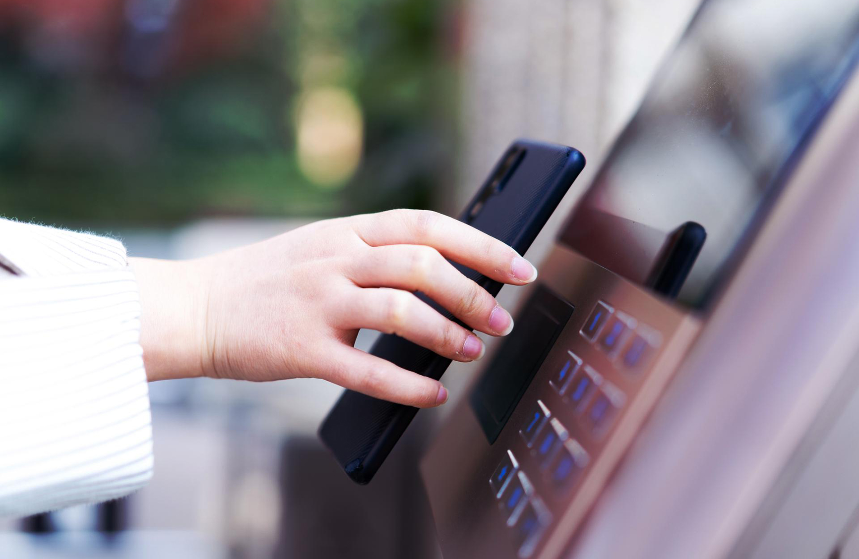 a womans hand holding a phone up to a bank machine